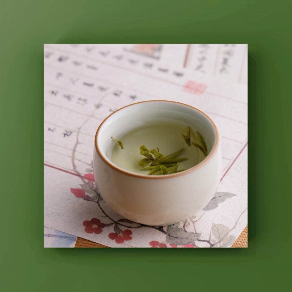 Green tea leaves steeping in a small white cup on a sheet of Chinese calligraphy paper