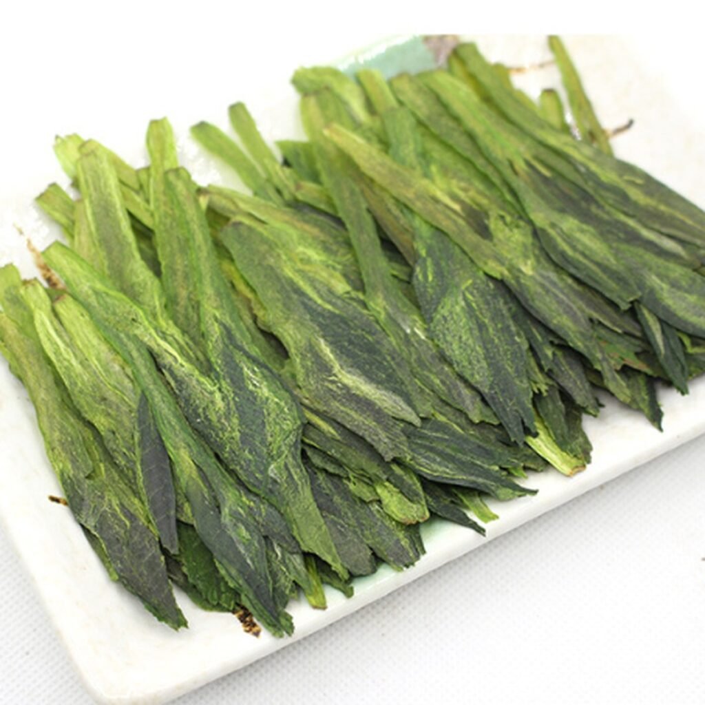 Long, flat Taiping Houkui leaves laid on a white plate, each a set of two leaves pressed around a bud