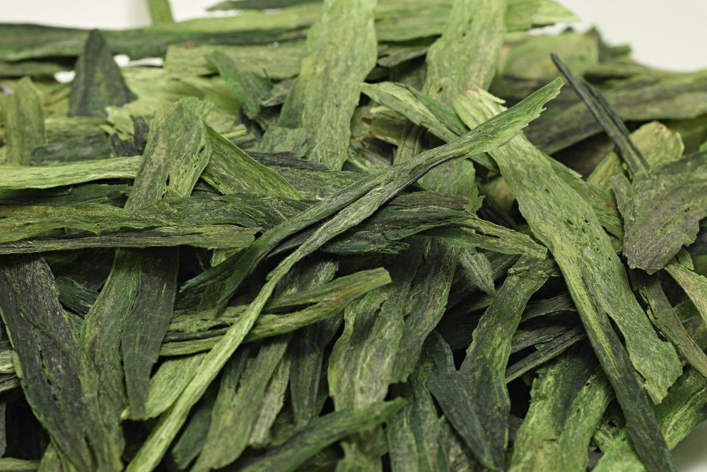 Close-up of dry Taiping Houkui leaves showing their flat surface, veins, and deep green color